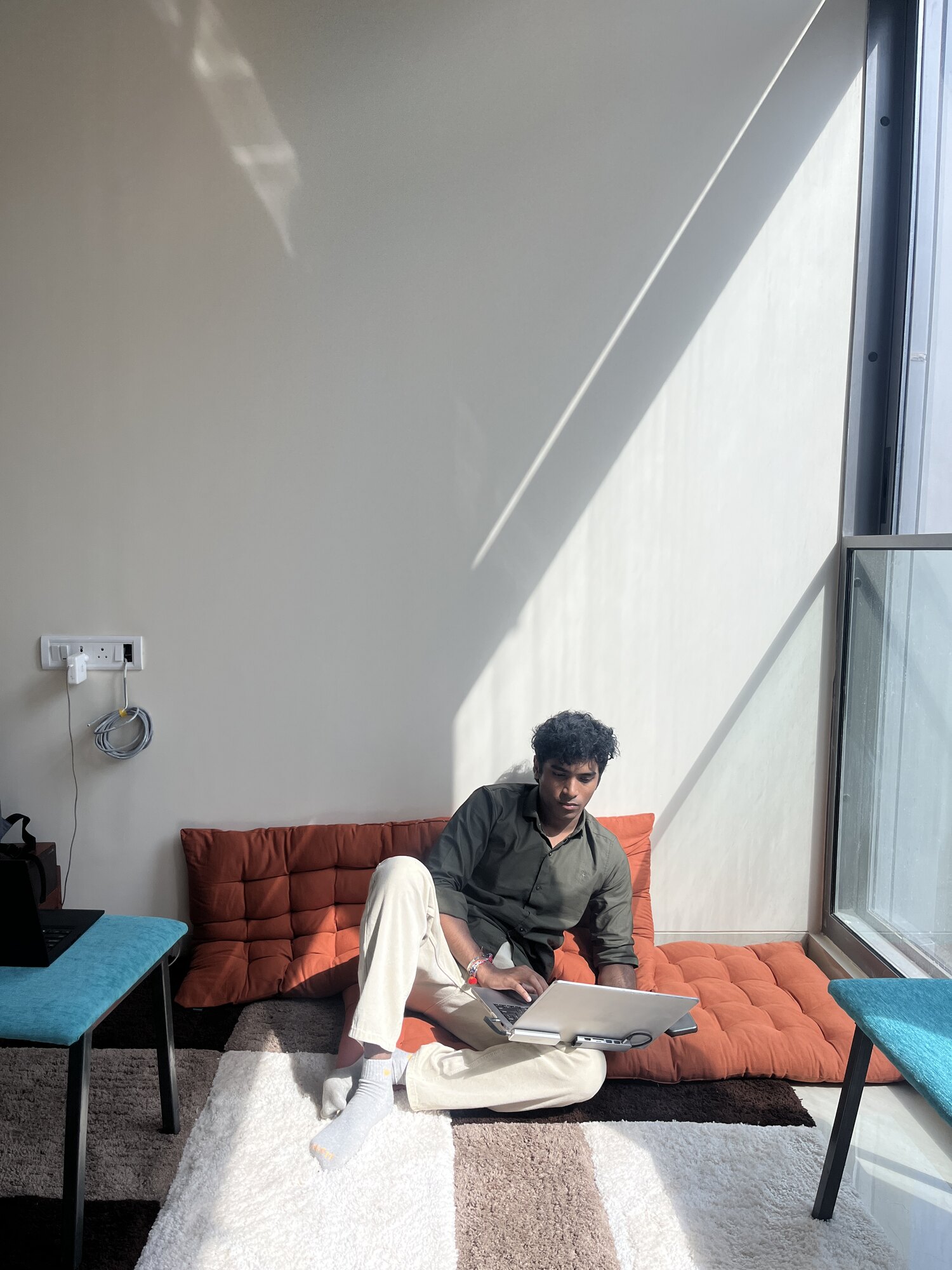 Yash working on his laptop in the sunlit office lounge